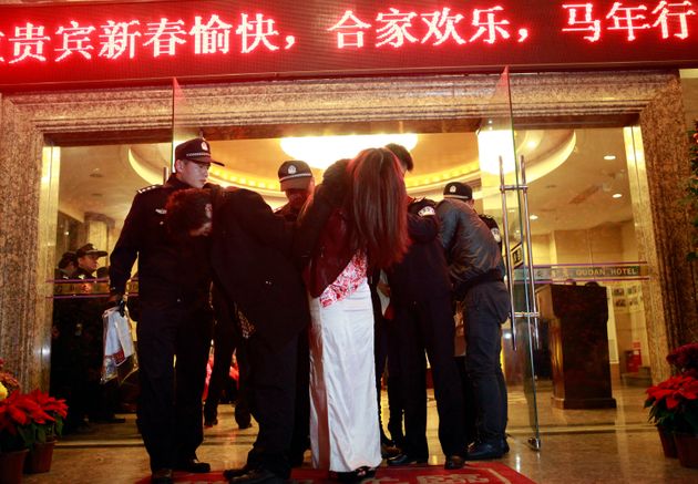 This picture taken late on February 9, 2014 shows Chinese police taking away alleged sex workers and clients at an entertainment center in Dongguan, southern China's Guangdong province.  A total of 67 people were arrested and 12 entertainment venues involved in the illegal sex trade were shut down after China Central Television (CCTV) revealed a dozen hotels in Dongguan offered sex services.       CHINA OUT      AFP PHOTO        (Photo credit should read STR/AFP via Getty Images)