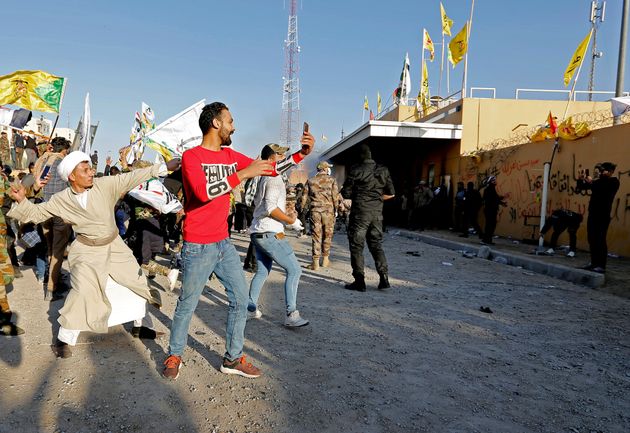 Protesters and militia fighters throw stones towards the U.S. Embassy during a protest to condemn air strikes on bases belonging to Hashd al-Shaabi (paramilitary forces), in Baghdad, Iraq December 31, 2019. REUTERS/Wissm al-Okili