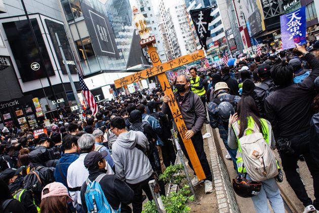 HONG KONG, CHINA - 2020/01/01: A protester holds a cross cursing Carrie Lam to hell during the demonstration.
Entering the 7th month of civil unrest, protesters marched the streets, calling for the five demands to be met. Demonstrators chanted slogans and sang songs. Police in riot gear appeared and arrested several masked protesters. (Photo by Willie Siau/SOPA Images/LightRocket via Getty Images)
