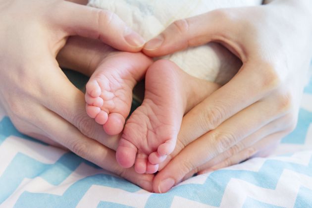 newborn baby legs in mother's hands folded by heart, the concept of motherhood, child care