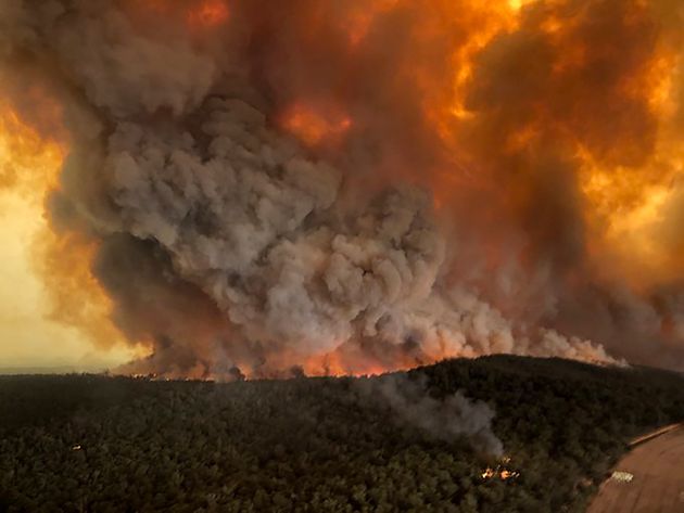In this Monday, Dec. 30, 2019, aerial photo, wildfires rage under plumes of smoke in Bairnsdale, Australia. Thousands of tourists fled Australia's wildfire-ravaged eastern coast Thursday ahead of worsening conditions as the military started to evacuate people trapped on the shore further south. (Glen Morey via AP)