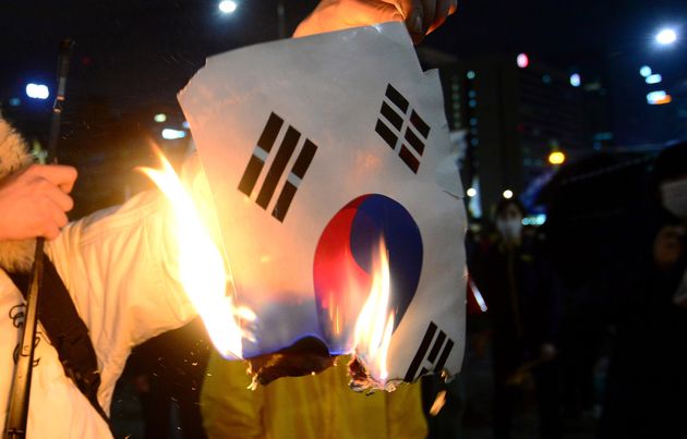 세월호 참사 1주년 추모집회 참가자인 김모씨가 2015년 4월 18일 오후 서울 광화문 앞에서 경찰과 대치하는 도중 태극기를 불태우고 있다. 