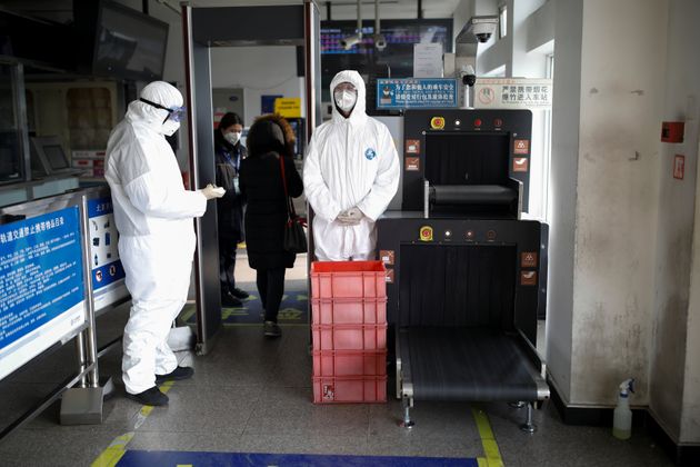 Staff members wearing protective suits and masks stand near the security check at a subway station, as the country is hit by an outbreak of the new coronavirus, in Beijing, China January 28, 2020. REUTERS/Carlos Garcia Rawlins
