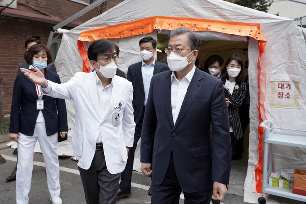 In this photo provided by South Korea Presidential Blue House via Yonhap News Agency, South Korean President Moon Jae-in, right, wearing a mask arrives to inspect the National Medical Center in Seoul, South Korea, Tuesday, Jan. 28, 2020. Moon on Tuesday visited the medical center in Seoul amid the outbreak of the new coronavirus. (South Korea Presidential Blue House/Yonhap via AP)