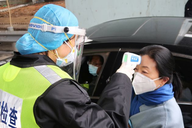 A security officer in a protective mask checks the temperature of a passenger following the outbreak of a new coronavirus, at an expressway toll station on the eve of the Chinese Lunar New Year celebrations, in Xianning, a city bordering Wuhan to the north, Hubei province, China January 24, 2020. REUTERS/Martin Pollard