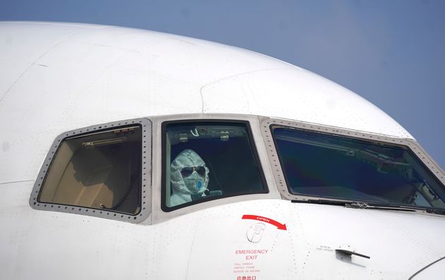 In this photo released by China's Xinhua News Agency, a pilot wearing a protective suit parks a cargo plane at Wuhan Tianhe International Airport in Wuhan in central China's Hubei Province, Tuesday, Jan. 28, 2020. Hong Kong's leader announced Tuesday that all rail links to mainland China will be cut starting Friday as fears grow about the spread of a new virus. (Cheng Min/Xinhua via AP)