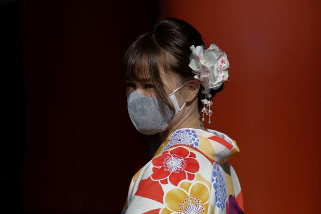 A tourist pauses for photos with her mask on at Sensoji Temple Thursday, Jan. 30, 2020, in Tokyo. The country began evacuating Japanese citizens on Wednesday from the Chinese city Wuhan hardest-hit by the virus. (AP Photo/Jae C. Hong)