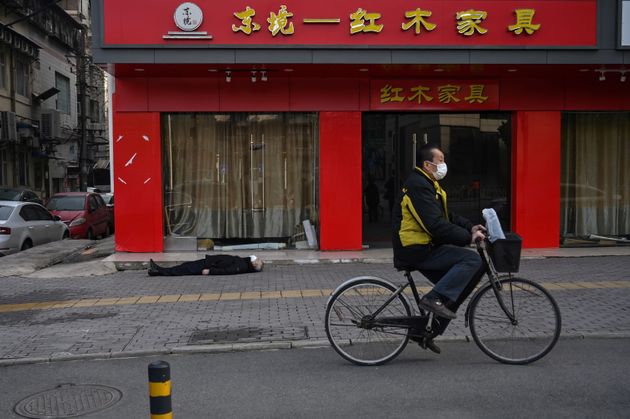 EDITORS NOTE: Graphic content / This photo taken on January 30, 2020 shows officials in protective suits checking on an elderly man wearing a facemask who collapsed and died on a street near a hospital in Wuhan. (Photo by Hector RETAMAL / AFP)