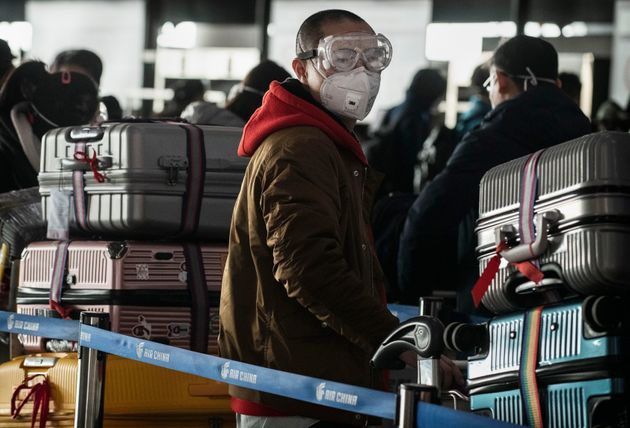 BEIJING, CHINA - JANUARY 30: A man wears a protective mask and goggles as he lines up to check in to a flight at Beijing Capital Airport on January 30, 2020 in Beijing, China. (Photo by Kevin Frayer/Getty Images)