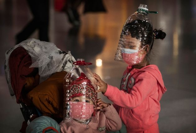 BEIJING, CHINA - JANUARY 30: Chinese children wear plastic bottles as makeshift homemade protection and protective masks while waiting to check in to a flight at Beijing Capital Airport on January 30, 2020 in Beijing, China.