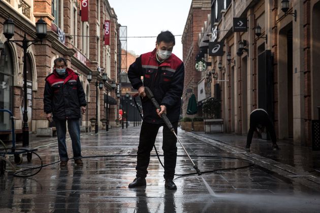 Cleaners wash the street with a high-pressure water gun on February 3, 2020 in Wuhan, Hubei province, China. 