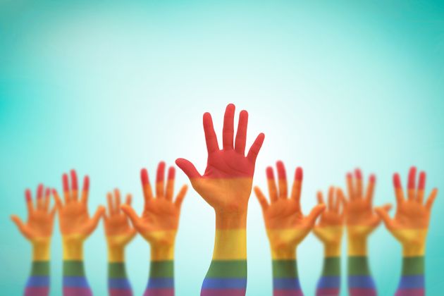 LGBT equal rights movement and gender equality concept with rainbow flag on people's hands up