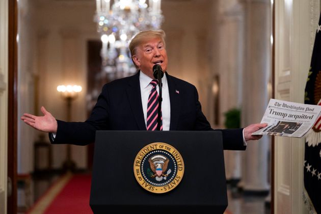 President Donald Trump holds up a newspaper tat reads 'Trump acquitted' during during an event celebrating his impeachment acquittal, in the East Room of the White House, Thursday, Feb. 6, 2020, in Washington. (AP Photo/Evan Vucci)