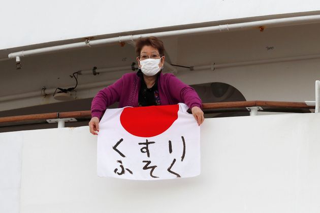A woman holds a Japanese flag that reads 'shortage of medicine' on the cruise ship Diamond Princess, where 10 more people were tested positive for coronavirus on Thursday, to the port as it is anchored at Daikoku Pier Cruise Terminal in Yokohama, south of Tokyo, Japan February 7, 2020. REUTERS/Kim Kyung-Hoon
