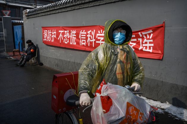 A Chinese woman walks past a sign saying 'Strong prevention, don't panic, believe in science, don't spread rumours' on February 7, 2020 in Beijing, China.