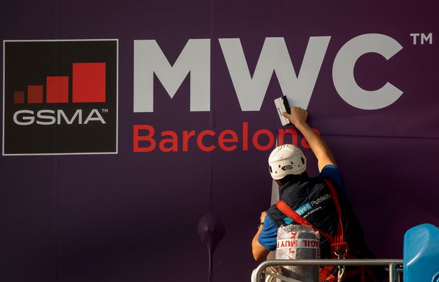 A worker fixes a poster announcing the Mobile World Congress 2020 in a conference venue in Barcelona, Spain, Tuesday, Feb. 11, 2020. (AP Photo/Emilio Morenatti)
