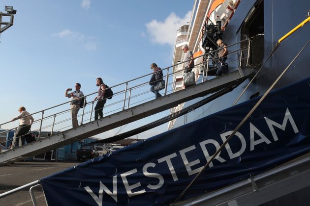 Passengers of the MS Westerdam, owned by Holland America Line  disembark from the MS Westerdam, at the port of Sihanoukville, Cambodia, Saturday, Feb. 15, 2020. After being stranded at sea for two weeks because five ports refused to allow their cruise ship to dock, the passengers of the MS Westerdam were anything but sure their ordeal was finally over. (AP Photo/Heng Sinith)