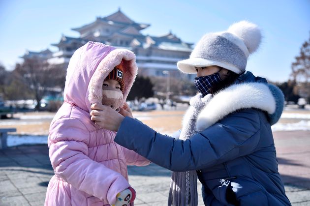 평양 시내에서 한 여성이 딸의 마스크 착용을 도와주고 있다. 평양, 북한. 2020년 2월6일.