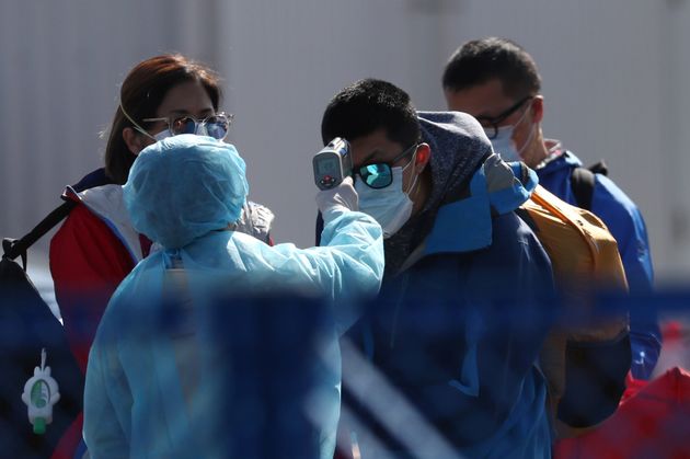 보호복을 입은 일본 보건당국 관계자들이 배에서 내린 승객들을 상대로 체온 측정을 실시하고 있다. 요코하마, 일본. 2020년 2월21일.