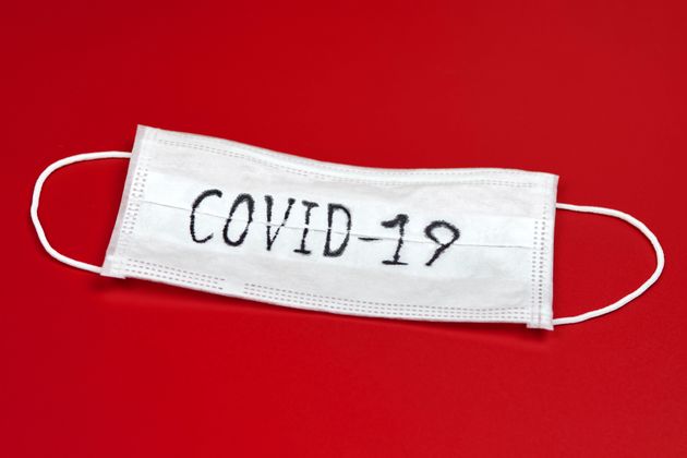 COVID-19 - Novel coronavirus - 2019-nCoV, WUHAN virus concept. Surgical mask protective mask with COVID-19 text. Chinese coronavirus outbreak. Red background.