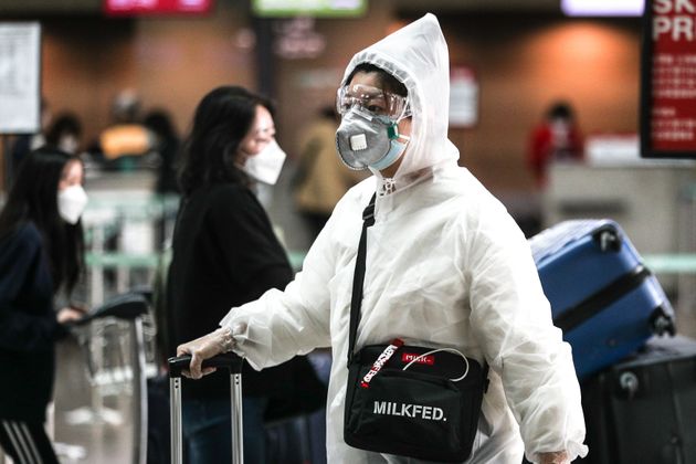 26일 오후 인천국제공항 제1터미널에서 코로나19 예방을 위해 비닐옷과 마스크를 착용한 여행객이 출국장으로 향하고 있다.