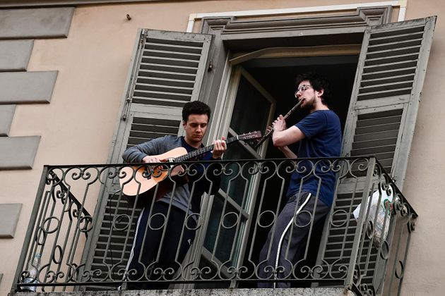 두 남성이 각각 기타와 플룻을 연주하고 있다. 토리노, 이탈리아. 2020년 3월13일.