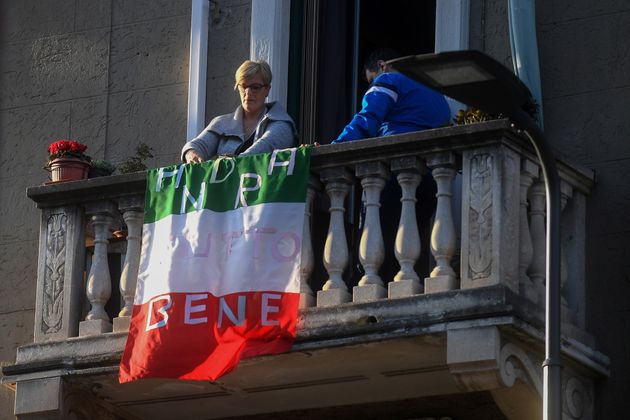 16일 밀라노의 한 아파트에서 시민이 '다 좋아질 거야'라고 쓰인 국기를 베란다에 내걸고 있다.