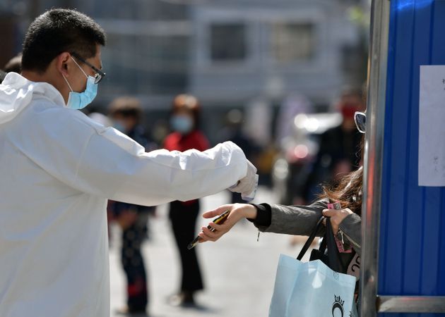 우한시 보건당국 관계자가 지나가는 시민의 발열을 확인하고 있다. 2020. 4. 15.
