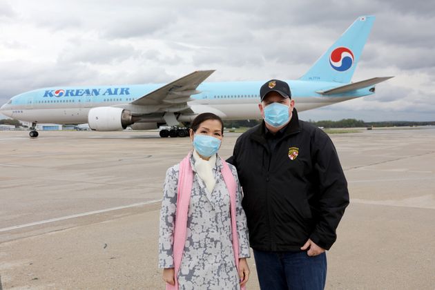 래리 호건 미국 메릴랜드 주지사와 그의 아내 유미 호건이 한국산 코로나19 검사키트를 싣고 볼티모어워싱턴 국제공항에 도착한 대한항공 특별 전세기 앞에서 포즈를 취하고 있다. 2020년 4월19일.