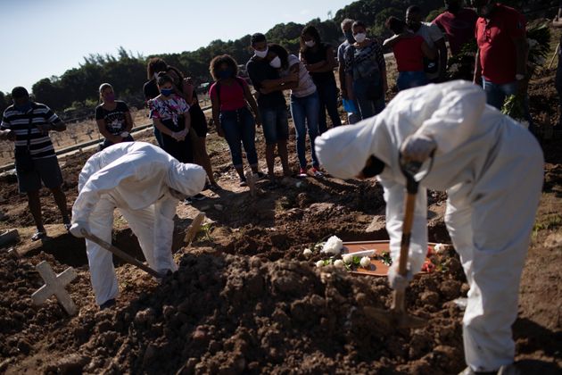 5월20일 리우데자네이루에서 방진복을 입은 묘지 직원들이 코로나19로 사망한 아만다 다 실바의 시신을 가족 친지가 지켜보는 가운데 매장하고 있다.