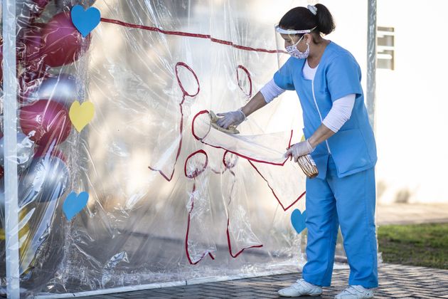 시설 직원인 간호사가 비닐 벽을 소독하고 있다.