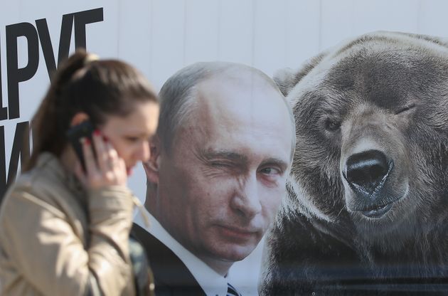 한 여성이 윙크하는 블라디미르 푸틴 러시아 대통령의 초상화와 곰의 그림 앞을 지나가고 있다. 2015. 5. 8. 