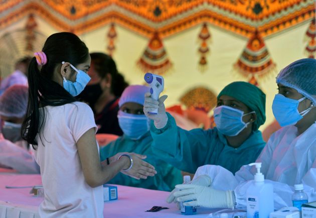28일 뭄바이의 한 코로나바이러스 검사장에서 의료진이 한 시민의 체온을 확인하고 있다.