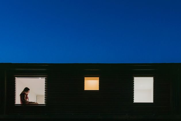 Night time view of home exterior - figure on laptop in the window