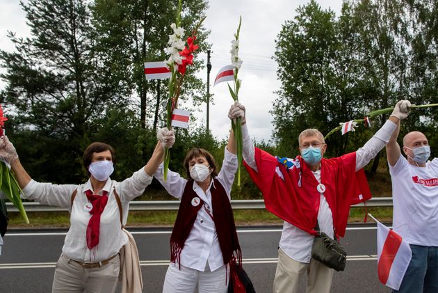 2020년 8월 23일 일요일 리투아니아 빌뉴스 동부를 가로지르는 리투아니아-벨라루스 국경 메디닌카이 인근에서 시위하는 동안, 사람들은 벨라루스의 깃발과 꽃을 들고 'Freedom Way'에 참가하고 있다.