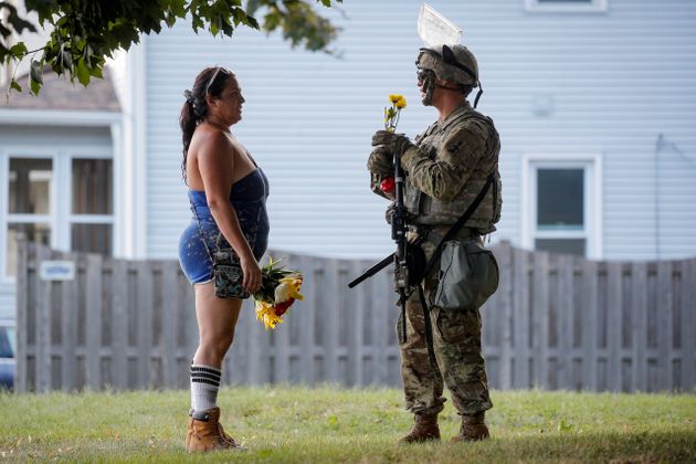 한 여성이 시위 진압을 위해 투입된 한 위스콘신 주방위군 군인에게 꽃을 건네고 있다. 커노샤, 위스콘신주. 2020년 8월28일. 
