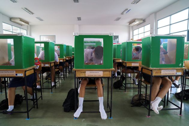 마스크와 얼굴 가리개를 착용한 학생들이 투표함을 재활용한 차단막 안에서 수업을 듣고 있다. 빠툼타니, 태국. 2020년 7월1일.