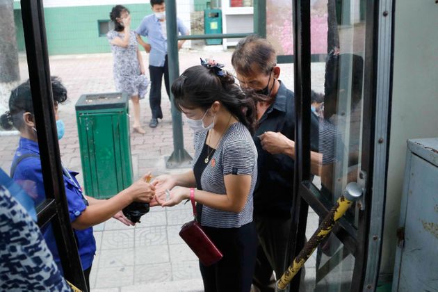8월 13일 버스를 타려는 평양 시민들의 모습. 모두 마스크를 썼으며, 손소독제를 직원으로부터 받고 있다. 