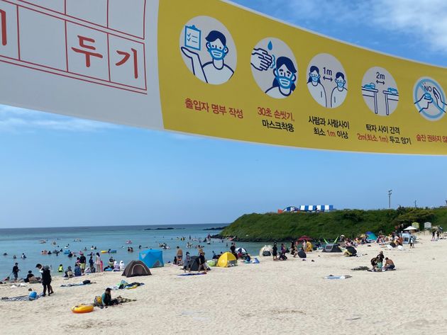 8월 24일 제주도의 한 해수욕장에 피서객들이 나온 가운데 방역 지침 안내 현수막이 걸려 있다.