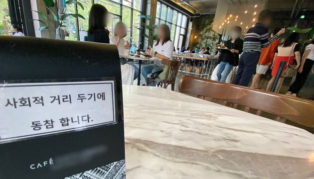 수도권의 사회적 거리두기 단계가 2.5단계에서 2단계로 2주간 조정된 지난 13일 서울 시내 카페거리의 한 카페에 시민들로 북적이는 가운데 거리두기 동참 의미로 테이블이 비어져 있다.