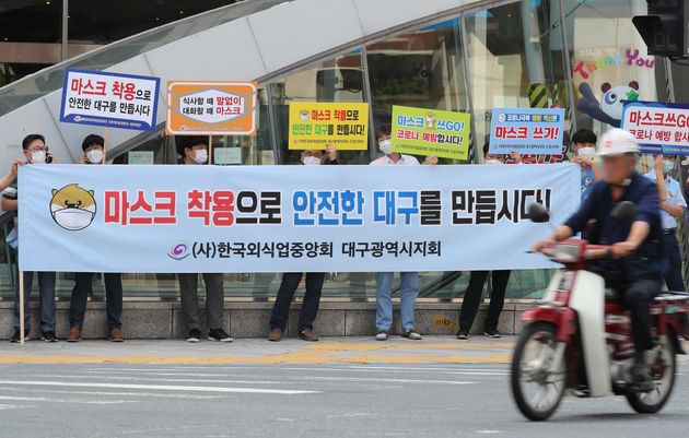 9월 14일 대구 중구 대구도시철도 중앙로역 지상 중앙네거리에서 한국외식업중앙회 대구지회 회원들이 '마스크 쓰Go 운동' 캠페인을 펼치는 가운데 마스크를 쓰지 않은 오토바이 운전자가 그 앞을 지나고 있다.