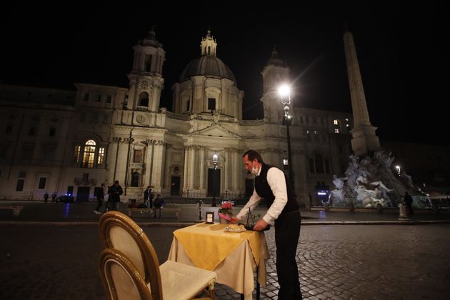 2020년 10월 23일 금요일 밤, 이탈리아 로마 나보나 광장의 한 레스토랑에서 웨이터가 테이블을 치우고 있다. 코로나19로 야간 통행금지가 시작되기 전이다. 봉쇄 조치를 완화하던 이탈리아는 일부 지역에서 23~24일 다시 야간 통행금지를 도입했다. 저녁 7시 30분부터 다음 날 오전 5시까지 통행이 금지됐다.