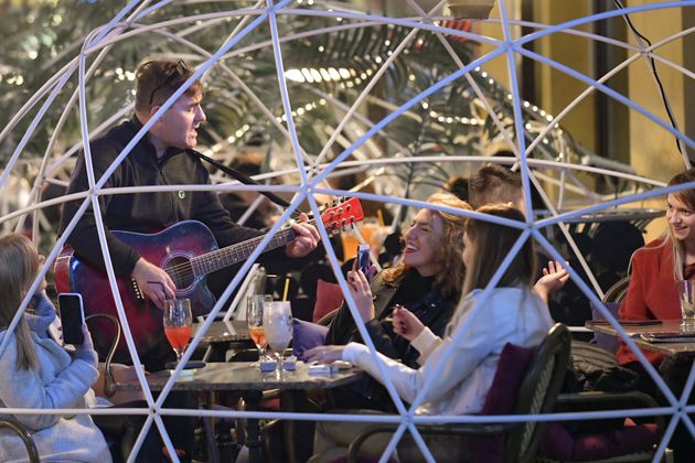 2020년 10월 23일 금요일, 루마니아 부쿠레슈티에 있는 레스토랑에서 한 뮤지션이 테이블 바로 앞까지 와서 기타 치며 노래 부르고 있다. 공연이 재미있는지 사람들이 활짝 웃는다.
