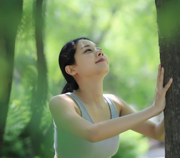 Woman stretching against tree in park