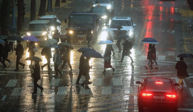 서울 서남권과 인천 등에 호우주의가 내려진 19일 오전 서울 종로구 도렴동 일대에서 우산을 쓴 시민들이 전조등을 켠 차량 앞을 지나고 있다.