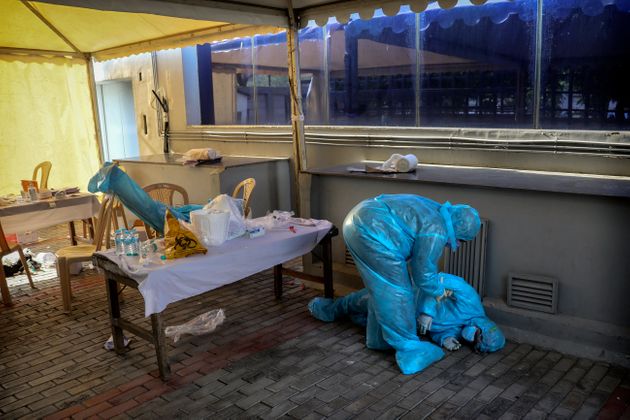 코로나19 검사소에서 탈진한 동료 의료진을 일으키는 한 의료인의 모습. 뉴델리, 인도. 2020년 4월27일.