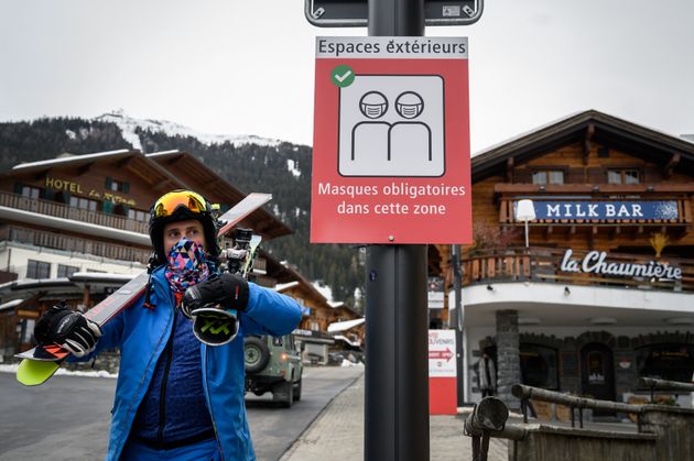 알프스의 유명 스키 관광지인 스위스 베르비에에서 한 스키 관광객이 '외부 공간 마스크 착용'을 알리는 안내판 앞을 지나고 있다. 2020년 12월22일.