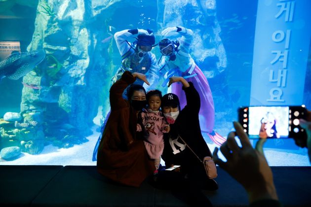 롯데월드 아쿠아리움 '디 오션(The Ocean)'에서 마스크를 쓴 관람객들이 한복을 입은 잠수부들과 함께 기념사진을 찍고 있다. 서울, 한국 2021년 1월3일.