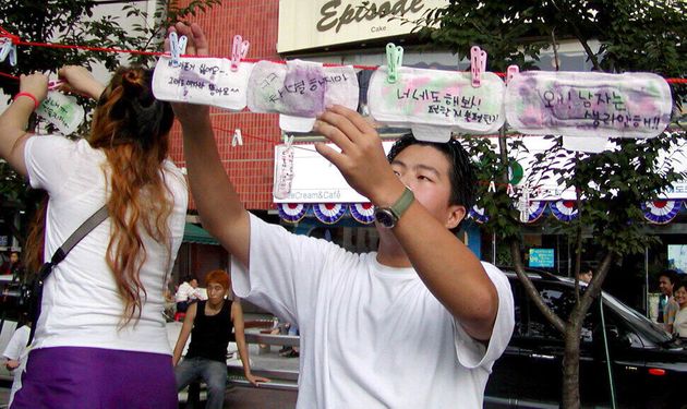 2002년 8월18일 서울 신촌에서 열린 월경페스티벌 거리홍보전에서 여성들이 월경에 대한 느낌을 쓴 생리대를 한 남성이 빨랫줄에 널고 있다. 1999년 4개 대학교 학생들의 연합 ‘불턱’이 개최한 월경페스티벌은 2007년까지 열렸다. 김아리 기자가 찍었다.
