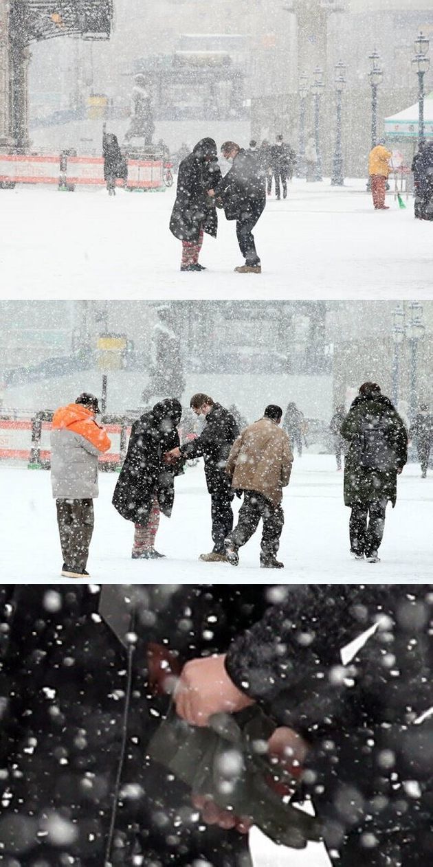 갑작스럽게 많은 눈이 내린 지난 18일 오전 서울 중구 서울역 앞에서 한 시민이 노숙인에게 자신의 방한점퍼와 장갑을 벗어 주고 있다.